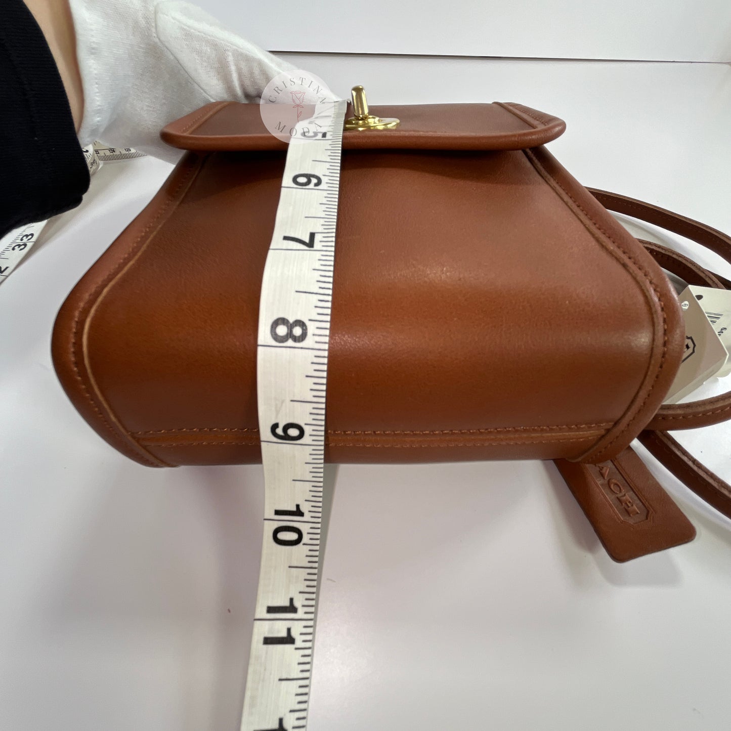 View of British tan vintage Coach Scooter Bag with tape measure showing bottom angle of height measurement