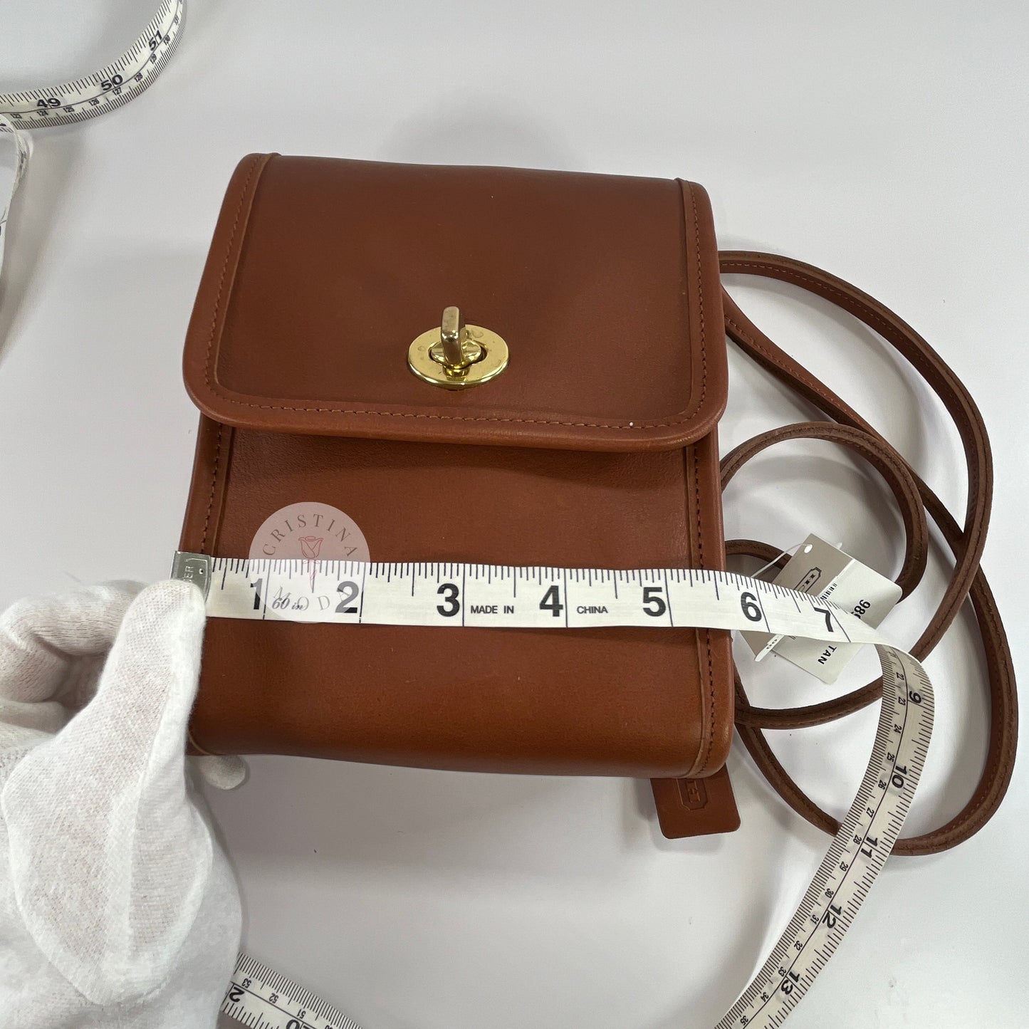 View of British tan vintage Coach Scooter Bag with tape measure showing width measurement of front of bag