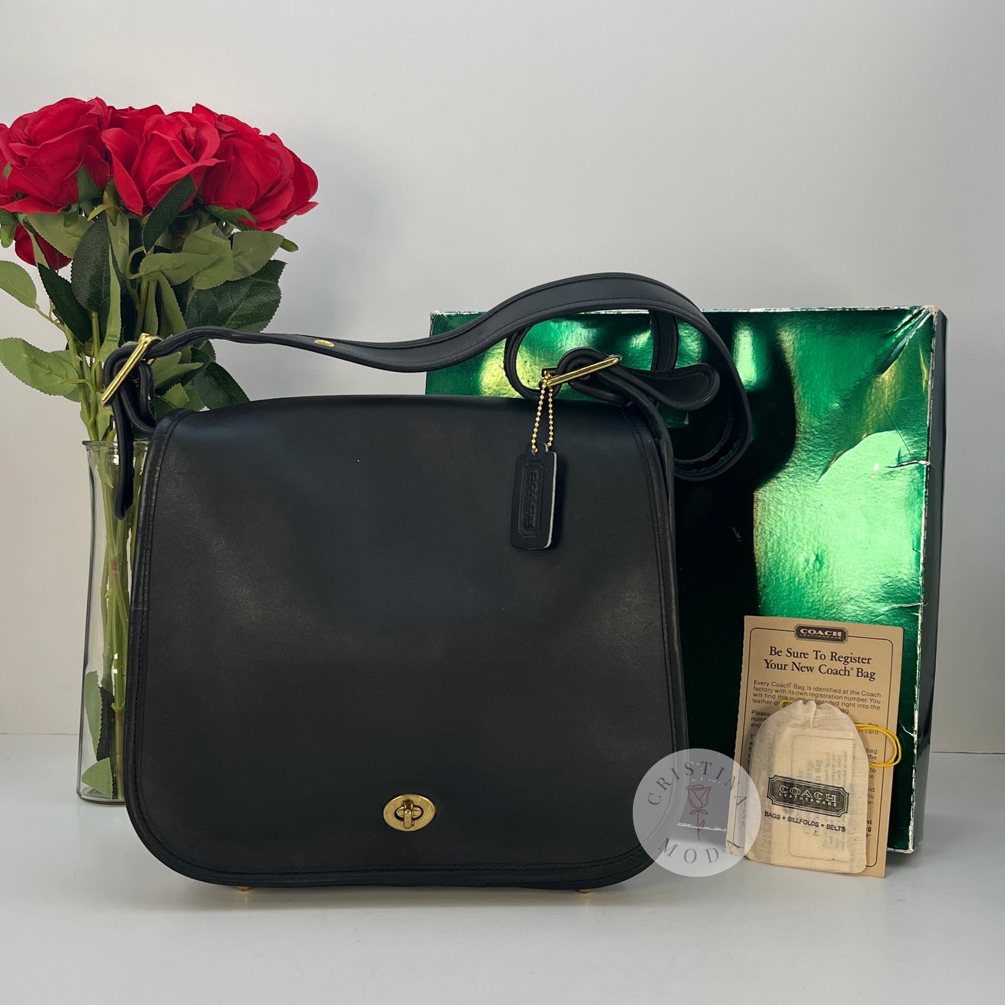 The cover shot of the vintage coach stewardess bag- the bag in front of the box and paperwork it comes with, with a bouquet of roses in the background