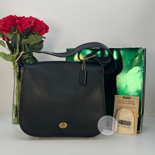 The cover shot of the vintage coach stewardess bag- the bag in front of the box and paperwork it comes with, with a bouquet of roses in the background