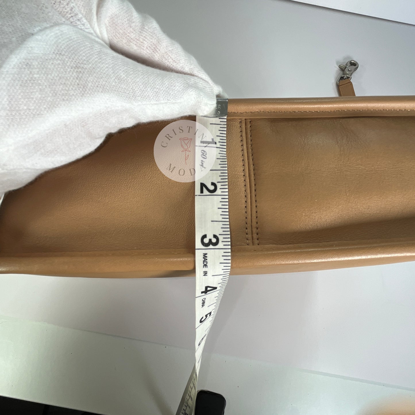 Photo showing measuring tape measuring the bottom of the bag- measuring tape shows the bottom is approximately between 3.25-3.5 inches wide 