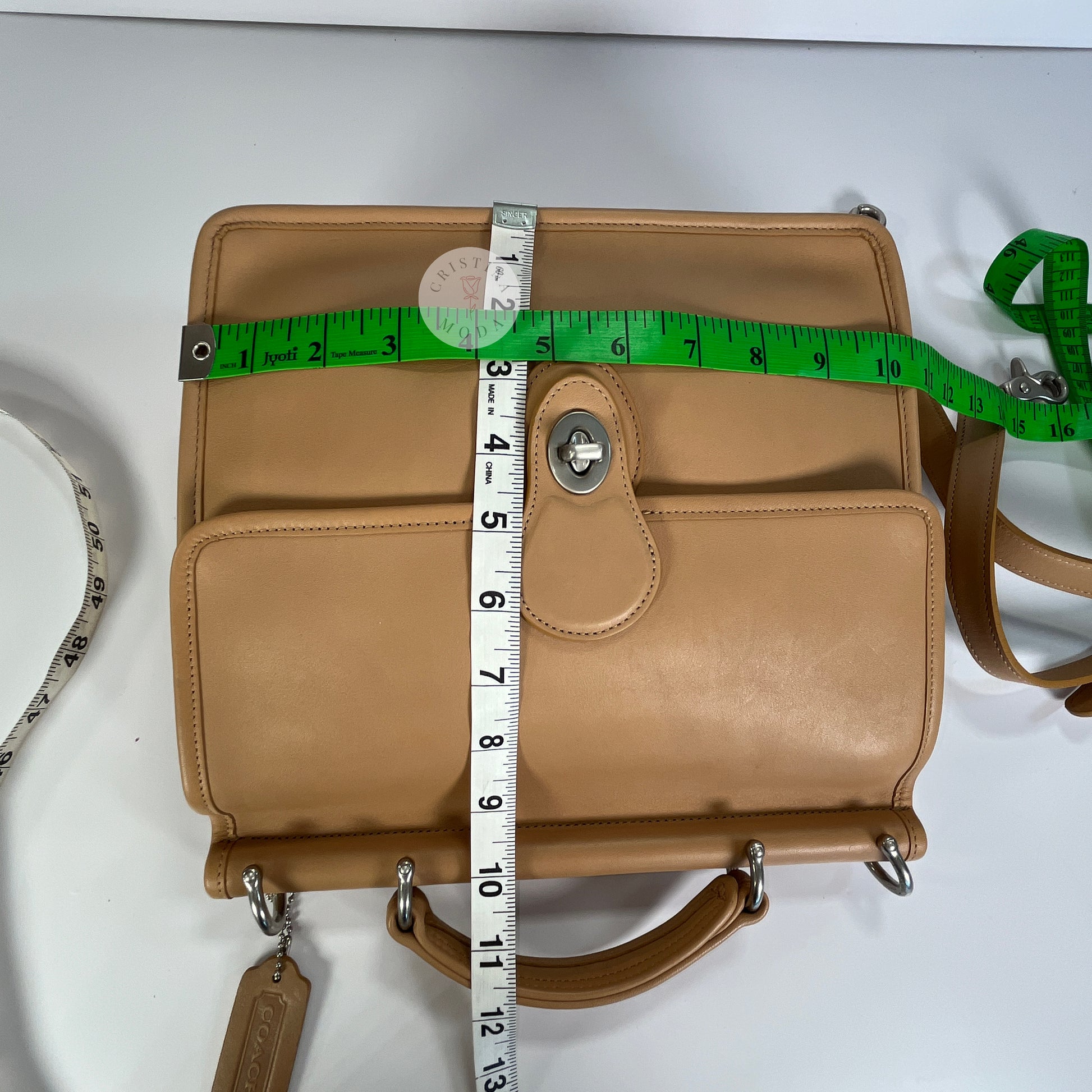 Photo showing measuring tapes laid across the bag to show photo measurements. Measurements show the bag is approximately 10.5-10.75 inches wide by approx. 10-10.25 inches tall. 